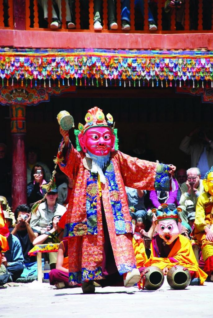 Guru Loden Chogse hóa thân của Đức Liên Hoa Sinh mang mặt nạ đỏ, y màu đỏ, tay cầm trống và bảo bình.